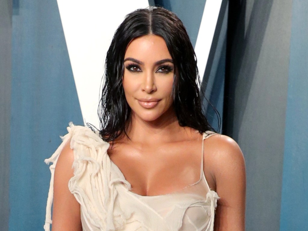 Kim Kardashan facing the camera and wearing a one shoulder strap dress. 