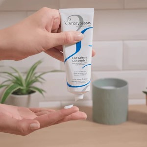 Hand holding a tube of Lait Crème concentré upside down and showing a drop of it on a finger