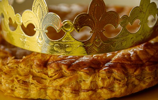 Zoom on the side of a golden cake with a partial view of a gold paper crown on it