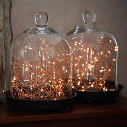 Garlands of lights under 2 glass domes. The garlands are on and show a soft, warm glow.
