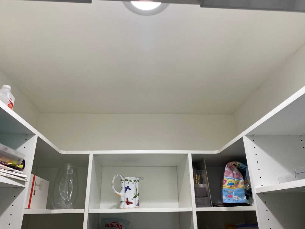 White ceiling above white shelves in an enclosed space